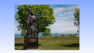 A bronze statue depicting a steelworker and their family located in a park.