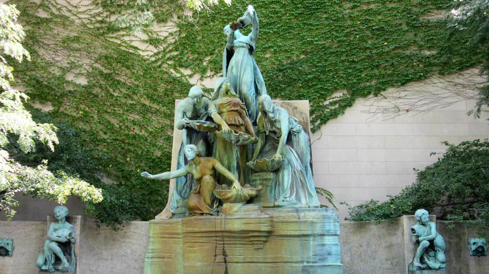 A statue of people in front of a wall.