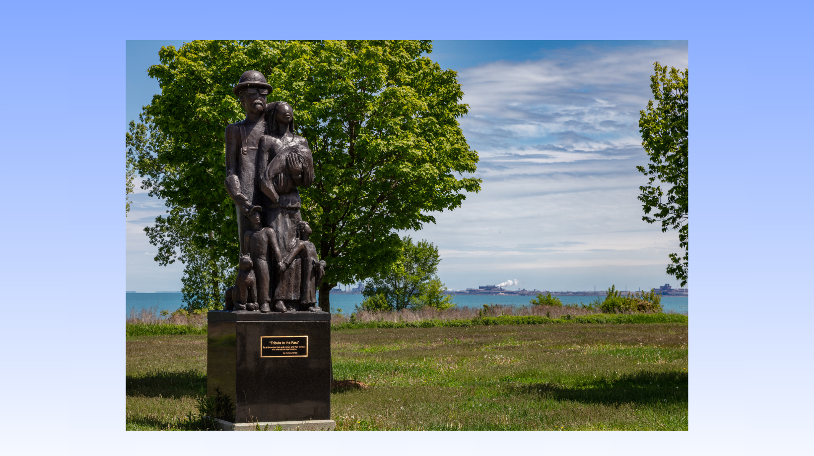 A bronze statue depicting a steelworker and their family located in a park.